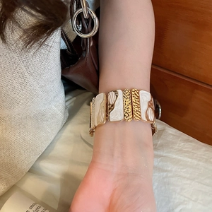 Detail of bohemian enamel square link bracelet with gold texture worn on wrist