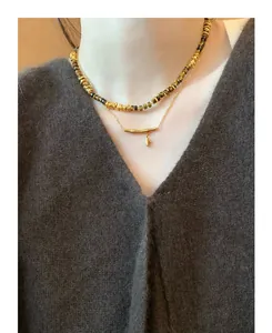 Detailed view of layered gold-plated necklaces with bamboo pendant and beaded tiger eye stones