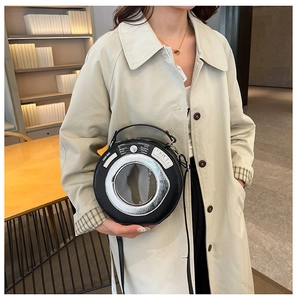 Detail view of a creative camera lens shaped shoulder bag with a transparent circular window