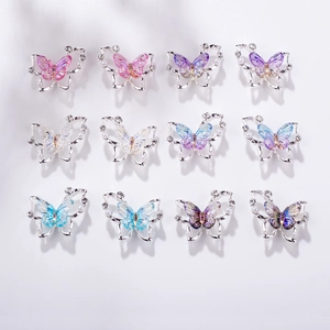 Flat lay macro of 12 mixed aurora butterfly nail art charms with pearls and rhinestones