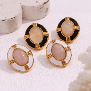 Detail of 18K gold plated oval natural stone earrings with a cross relief pattern