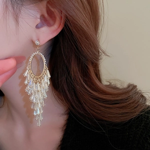Macro side view of elegant gold tassel earrings with clear crystals on female model