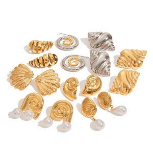 Detailed view of gold and silver shell-shaped earrings with pearls on white background