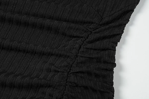 Macro detail of black ribbed knit fabric showing side ruched texture on dress