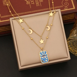 Detail of gold double-layered necklace with star moon charms and blue evil eye pendant