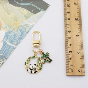 Macro shot of panda and bamboo pendants on gold keychain with ruler measurement