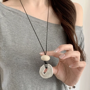 Minimalist long necklace with irregular cream and white geometric pendants on black cord