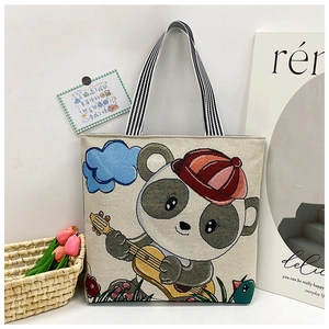 Detail of cute cartoon panda illustration on linen tote bag with striped straps
