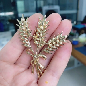 Back view of a gold wheat stalk brooch featuring a secure safety pin fastener