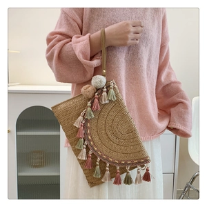 Detail of straw woven clutch featuring colorful tassels and bohemian pompom decorations