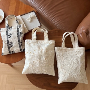 Detailed top view of French vintage lace embroidered tote bags on a wooden table