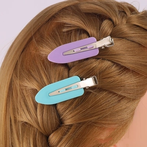 Detail showing blue and purple 6cm duckbill hair clips worn on braided golden brown hair
