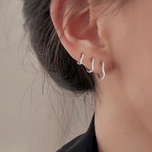 Close-up of model wearing three silver hollow bow hoop earrings with sparkling zircons