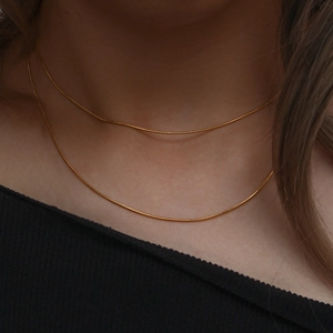 Close-up of layered delicate gold snake bone necklaces on neck for minimalist style