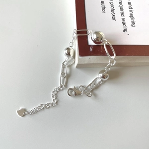 Detail of 925 sterling silver beaded bracelet with heart charm on a minimalist background