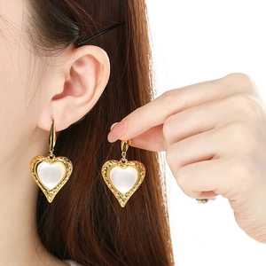 Classic golden heart earrings with cat eye stone inlay on model side view
