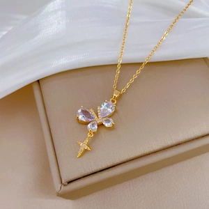 Elegant gold butterfly and cross necklace with sparkling crystals on beige jewelry box