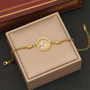 Close-up of a gold twist chain necklace with an evil eye and clover charm in a jewelry box