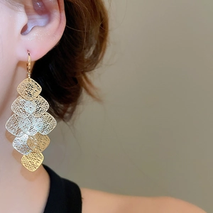 Close-up of geometric hollow tassel earrings with two-tone layered diamond mesh design