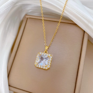 Detail of gold square pendant necklace with micro-pave crystals on white satin
