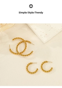 Detailed view of twisted gold-plated C-shape hoop earrings in two sizes on a stone display