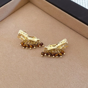 Gros plan de boucles d'oreilles vintage en métal doré martelé avec perles brunes