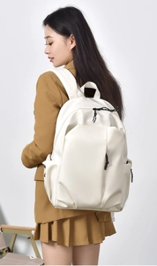 Side view of a large white campus backpack with black zippers on a female student model