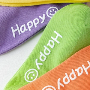 Detail of colorful cotton socks with Happy text and smiley face non-slip silicone grips
