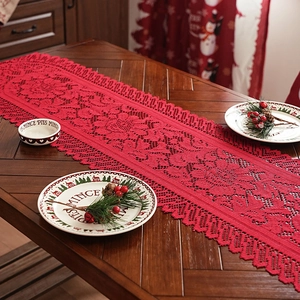 Red Christmas lace table runner with intricate festive patterns on a dark wood dining table