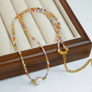 Close-up of natural pearl and colorful crystal beaded necklace on wooden jewelry box