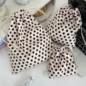Detailed set of three polka dot canvas drawstring bags in different sizes on white desk