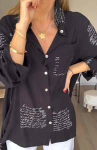 Detail eines schwarzen Langarmhemds mit weißem Schriftdruck und Button-Down-Kragen