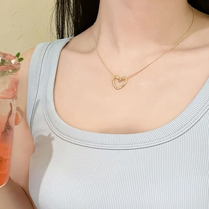 Élégant collier pendentif cœur en titane doré sur chaîne serpent porté par un modèle