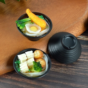 Miniature Japanese ramen and udon noodle bowls with shrimp and egg on wood background