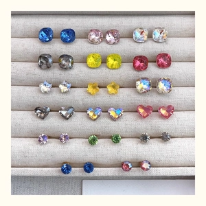 Close-up of assorted colorful crystal stud earrings in various shapes on display