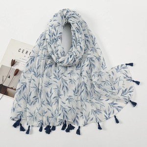 Detail of white cotton linen scarf with blue leaf print and delicate fringe tassels
