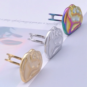 Detail of bear paw print rings in gold, silver, and iridescent finishes on textured metal