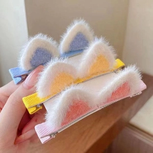 Close-up of three plush cat ear hair clips in blue, yellow, and pink colors