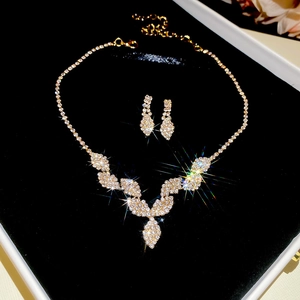 Detailed view of luxury gold fringe necklace and teardrop earrings on black velvet