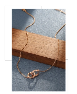 Detailed shot of a rose gold double ring necklace with pavé crystal on dark wood surface