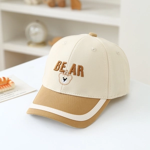 Close-up of embroidered bear and lettering on beige and brown cotton kids baseball cap