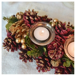 Macro detail of red pine cone candle holder with gold berries and glass tea light cup