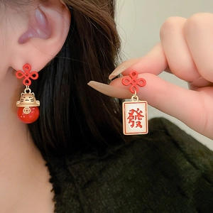 Detail of asymmetric Chinese style earrings with red knot, lucky cat and mahjong tile