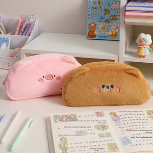 Close-up of pink and brown plush pig and bear pencil cases on a cozy desk setup