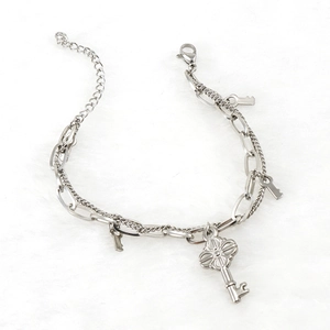 Detail of silver dual-layer chain bracelet featuring multiple key-shaped charms on fur background