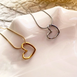 Close-up of minimalist gold and silver hollow heart pendants on delicate snake chains