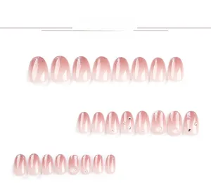 Detail view of pink gradient press-on nails with glitter tips, pearls and 3D hearts