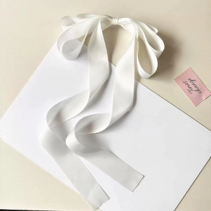 Detail of white satin ribbon bow with long streamers and smooth glossy texture