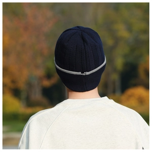 Vista posteriore del berretto in maglia a coste blu navy con strisce grigie nel bosco