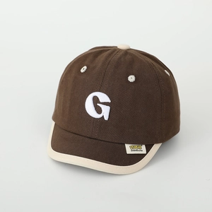 Detail of child's baseball cap with white towel embroidered G and brand label on brim